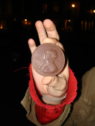 Photo, trouvée sur Internet, de la main d'une personne tenant une pièce en chocolat dont le côté face reproduit le portrait d'Alfred Nobel tel qu'il figure sur les médailles associées au prix qui porte son nom. On a donc ici un authentique prix Nobel en chocolat, ce qui n'a rien à voir avec ce dont je parlais dans ce pouet mais me semble être la meilleure façon de l'illustrer.