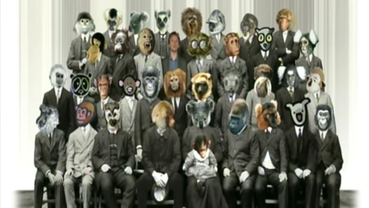 « Photo de famille des primates », encore une fois une capture d'écran du documentaire Espèces d'espèces. On voit une vieille image en noir et blanc d'un certain nombre de types en costard, sauf que leurs têtes ont été remplacées par des têtes de singes (dans des styles différents, certaines sont des photos, d'autres des dessins, on en a même une qui ressemble à une tête de peluche). Le présentateur du documentaire, représentant toujours Homo Sapiens, est présent sur l'un des rangs arrières, la main posé sur l'épaule du tarsier situé à côté de lui. « Photo de famille des primates », encore une fois une capture d'écran du documentaire Espèces d'espèces. On voit une vieille image en noir et blanc d'un certain nombre de types en costard, sauf que leurs têtes ont été remplacées par des têtes de singes (dans des styles différents, certaines sont des photos, d'autres des dessins, on en a même une qui ressemble à une tête de peluche). Le présentateur du documentaire, représentant toujours Homo Sapiens, est présent sur l'un des rangs arrières, la main posé sur l'épaule du tarsier situé à côté de lui.