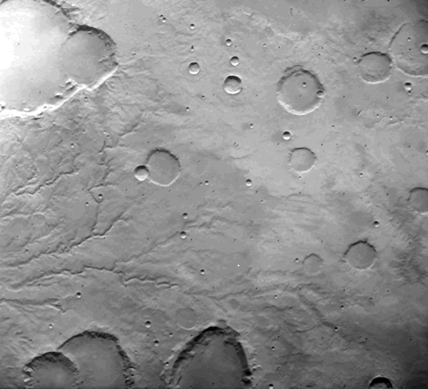 Photo de Mars prise depuis l'orbite, en noir et blanc, montrant un paysage globalement plat avec plusieurs cratères d'impact de tailles variables, mais où on peut surtout voir des lignes serpenter, en particulier sur la gauche de l'image, qui ressemblent beaucoup à la forme vue d'en haut du lit d'une rivière. Il n'y a bien sûr pas d'eau liquide ici, mais ça ressemble beaucoup à ce qu'on observerait si une rivière avait creusé le paysage en passant où elle peut avant de s'assécher complètement, ne laissant derrière elle que les reliefs de son passage.