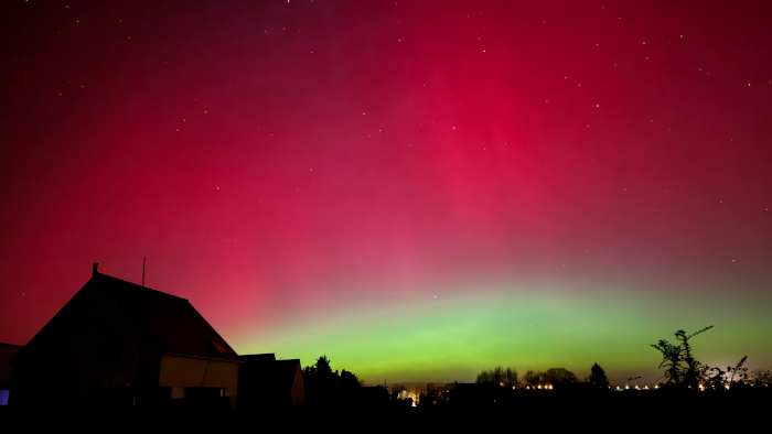 Photo prise par mon collègue lors de l'aurore du 19 janvier 2026, à proximité de Lannion. On voit en bas de l'image une maison plongée dans l'obscurité et, dans le lointain, quelques arbres et la lumière de lampadaires. Au dessus, le ciel nocturne est presque entièrement occupé par deux grosses zones lumineuse, une présentant plusieurs nuances de vert juste au dessus de l'horizon, et une autre rouge-violacée occupant la quasi-totalité du ciel restant, soit environ la moitié de l'image. Quelques étoiles peuvent être devinées à travers la partie rouge.