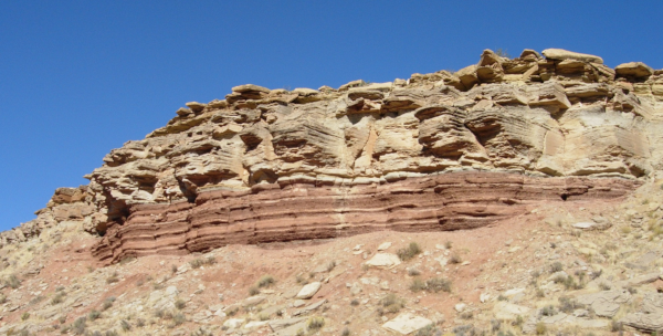 Roches sédimentaires cette fois venues de la Terre, en l'occurrence des USA, et datées du Trias (le début de l'ère Mésozoïque, où les dinosaures et les mammifères sont apparus), que j'ai trouvé sur la page Wikipédia dédiée à ce sujet. On reconnaît le même type de structures en couches correspondant aux empilements de dépôts que sur l'image précédente, et comme les roches sont environs de la même couleur, on pourrait penser que les deux viennent de la même formation… même si le fait que celle-ci soit originaire de la Terre est rendu assez évident par le ciel bleu et les quelques plantes éparses qu'on voit pousser en bas de l'image.