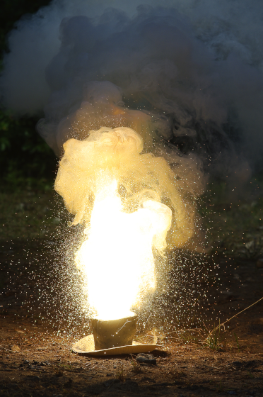 Photographie, illustrant actuellement la page Wikipédia francophone dédiée aux réactions d'oxydoréduction, d'une réaction d'aluminothermie, se produisant entre de l'aluminium et certains oxydes métalliques. On voit un récipient posé au sol dont s'élève ce qui ressemble à une flamme, encore que ça n'ait pas vraiment la même tête que les flammes dont nous avons plus souvent l'habitude, notamment à cause de la couleur, mais on reparlera sans doute un peu plus de ce qui donne leurs couleurs aux flammes à une autre occasion, si ça vous intéresse.