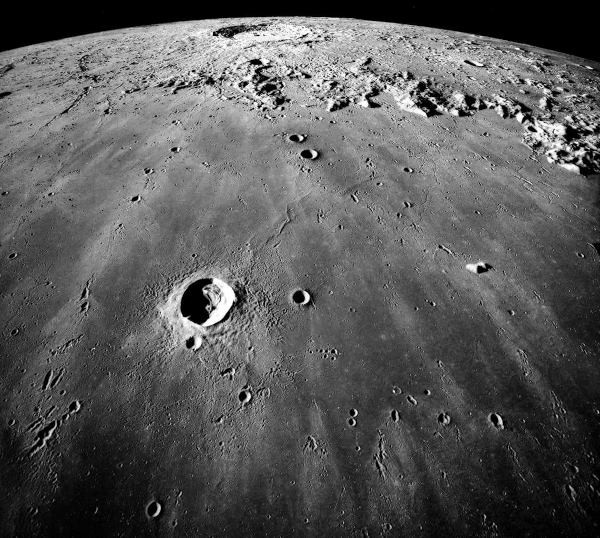 Photo trouvée sur la page Wikipédia de la Lune et prise par l'équipage d'Apollo 17 montrant la mer des Pluies, une formation géologique de plus d'un millier de kilomètres de large. La zone résulte d'abord d'un impact gigantesque survenu il y a un peu moins de quatre milliards d'années, qui a ensuite été rempli de lave. La photo nous montre au premier plan une zone sombre et peu accidentée, avec un nombre de cratères (d'impact, pas volcaniques) plutôt limité, qui correspond à la mer des Pluies elle-même, et un peu plus loin, l'océan des Tempêtes, une zone avec davantage de reliefs et une surface globalement plus claire. On voit dans la mer des Pluies un cratère plus gros que les autres : il a été nommé Pythéas, en référence au marin phocéen qu'on a évoqué la semaine dernière. Plus loin, dans l'océan des Tempêtes, on remarque un cratère encore plus gros : il a été nommé Copernic en référence à l'astronome du seizième siècle à qui on doit le modèle héliocentrique.