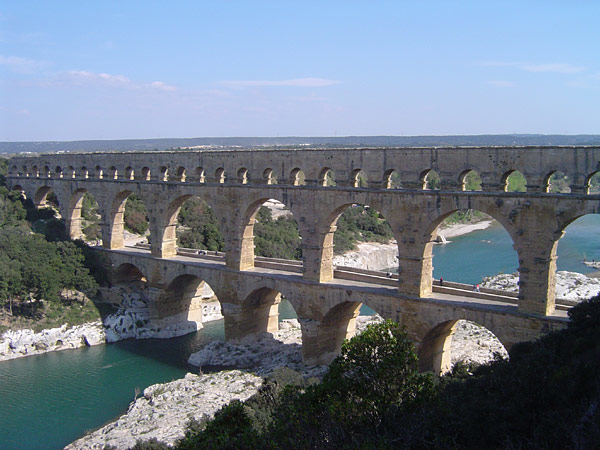 Photo du pont du Gard, trouvée sur la page Wikipédia dédiée aux aqueducs, car il en porte un (On voit globalement une rivière passée entre deux berges couvertes d'arbres, et un pont à deux étages qui traverse cette rivière, le premier servant à passer aux gens, et le second servant à l'eau). On était encore loin de connaître tous les détails théoriques à l'époque, mais les fontaines romaines alimentées par ces aqueducs montraient déjà une certaine maîtrise pratique du phénomène dont il va être question ici.