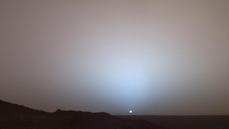 Coucher de Soleil photographié depuis Mars par le rover Spirit : le ciel est marron au lieu d'être bleu, et autour du Soleil, la lueur du coucher est bleue au lieu d'être rouge. Le Soleil est aussi plus petit que sur Terre, puisqu'il est vu de beaucoup plus loin.