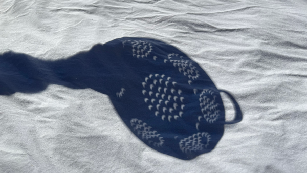 Photo, trouvée sur Wikimédia Commons, montrant l'ombre d'une passoire sur ce qui semble être un drap blanc pendant une éclipse. On voit, par les multiples trous de la passoire, la forme d'un croissant de Soleil, puisque la Lune est en train d'en masquer une partie. Ça n'offre évidemment pas de grossissement comme peut le faire une lunette astronomique, mais ça reste un moyen simple, sûr et efficace de regarder le phénomène, ce qui est donc plutôt cool.