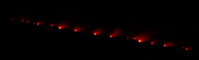 Photo prise par le télescope spatial Hubble montrant plusieurs fragments de la comète après sa dislocation. Chacun ressemble à une comète miniature, tous de couleur rougeâtre et bien alignés.