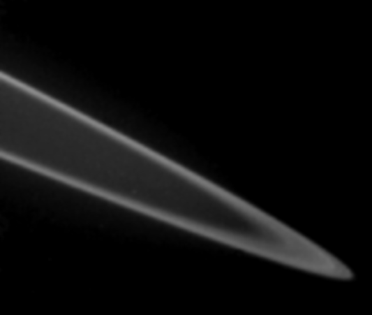 Photo des anneaux de Jupiter prise par la sonde Voyager 2 et trouvée sur la page Wikipédia dédiée à ces anneaux. On voit globalement, sur fond noir, la forme très caractéristiques des anneaux, on pourrait avoir un rendu du même style en photographiant l'extrémité des anneaux de Saturne (la planète n'est pas dans le cadre, on voit juste le disque de matière qui tourne autour).