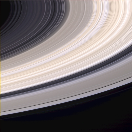 Photos des anneaux de Saturne en vraies couleurs, prise par la sonde Cassini et trouvée sur Wikimédia Commons, montrant une vue centrée sur les anneaux (la planète apparaîtrait si elle était prise dans le cadre sur la gauche de l'image, en haut). Cette image, comparée à celles des anneaux des autres planètes montrées dans les pouets précédents, permet de voir que les anneaux de Saturne sont de loin les plus brillants et les plus développés.
