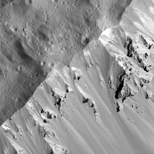 Photo prise par la sonde Dawn du rebord d'un cratère à la surface de Cérès. Cette photo à été prise à une altitude de 33 kilomètres, c'est l'un des clichés pris au plus près de la planète naine. On y voit un relief montagneux avec des ombres, et des différences de luminosité (la photo est en noir et blanc) laissant supposer des différences de composition dans la surface. Sur la partie extérieure, on voit également quelques cratères beaucoup plus petits, signe que Cérès a reçu des impacts d'objets de tailles très variables. Photo prise par la sonde Dawn du rebord d'un cratère à la surface de Cérès. Cette photo à été prise à une altitude de 33 kilomètres, c'est l'un des clichés pris au plus près de la planète naine. On y voit un relief montagneux avec des ombres, et des différences de luminosité (la photo est en noir et blanc) laissant supposer des différences de composition dans la surface. Sur la partie extérieure, on voit également quelques cratères beaucoup plus petits, signe que Cérès a reçu des impacts d'objets de tailles très variables.