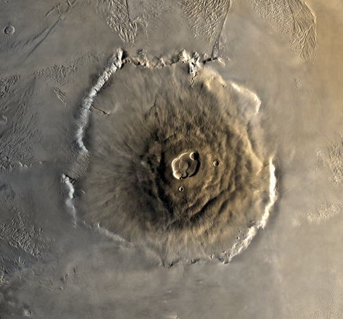 Photo d'Olympus Mons prise par la sonde Viking. Olympus Mons est un volcan éteint, le plus grand de Mars, et en fait la plus grande montagne du système solaire, puisqu'il est haut comme trois fois notre Mont Everest, et large comme la France métropolitaine. Il résulte vraisemblablement d'un point chaud, et, s'il a pu grandir autant, c'est parce que Mars n'a pas d'activité tectonique (sur Terre, le déplacement des plaques fait que les points chauds font naître plusieurs volcans différents au fil du temps, ce qui donne des archipels volcaniques comme les îles Canaries).