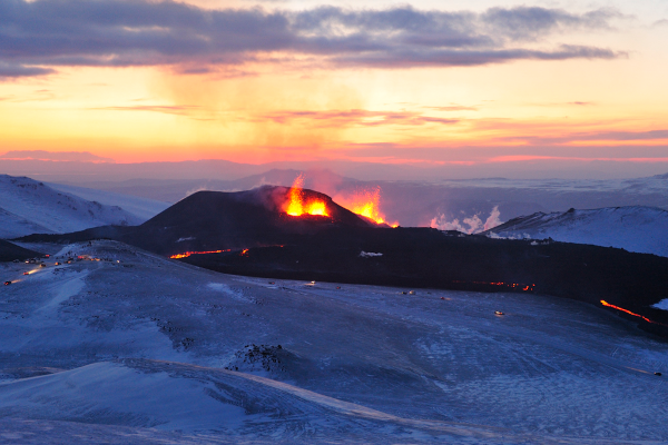 Photo (disponible notamment sur Wikimédia Commons) montrant l'éruption de 2010 du volcan islandais Eyjafjöll (le nom que vous avez peut-être croisé à l'époque, « Eyjafjallajökull », désigne en fait le glacier situé sur ce volcan), qui avait à l'époque interrompu le trafic aérien sur une bonne partie de l'Europe, ce dont on ne va pas se plaindre. On voit une chaîne de montagnes principalement recouvertes de neige et de glace, mais sur celle du centre, plus sombre, on voit nettement des jets de lave, et quelques lueurs indiquent le déplacement de la coulée.