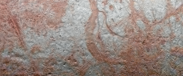 Vue de la surface d'Europe prise par la sonde Galileo (on ne voit que la surface, comme une vue aérienne sur Terre). Deux couleurs se distinguent nettement : le blanc de la glace, et des zones un peu plus brunes où elle est mélangée à du sel. Aucune ouverture ne laisse deviner quoi que ce soit de ce qu'il se passe là-dessous.