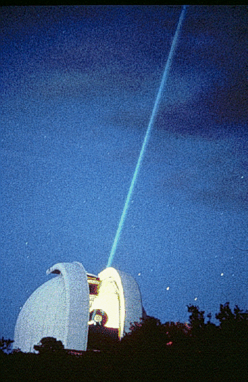 Photo, trouvée sur la même page Wikipédia, d'un observatoire participant à cette expérience. On voit une coupole (celle de l'observatoire Mc Donald, visiblement) ouverte en bas, avec un trait lumineux droit qui traverse l'image en partant de là. Il s'agit du faisceau laser, qui pointe en direction de la Lune, non visible sur l'image. Notons qu'à la vitesse de la lumière, la distance Terre-Lune met quand même environ une seconde à être parcourue.