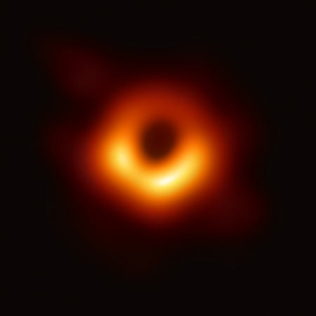 Image du trou noir M87* prise par l'Event Horizon Telescope. On voit, sur fond noir, une boule noire entourée d'une sorte de nuage flou de matière majoritairement rouge-orange, avec sur le devant des zones plus lumineuses tirant vers le jaune, voire le blanc.