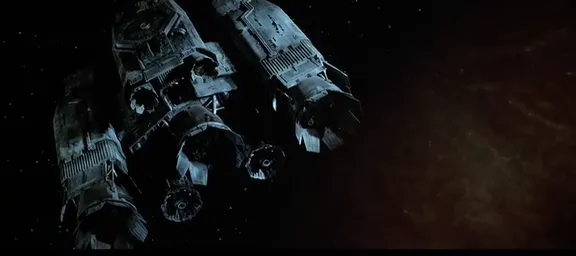 Capture d'écran du film Alien (premier du nom) dans lequel on voit l'USCSS Nostromo, un remorqueur spatial, commencer son approche de la planète LV-426 où les ennuis vont commencer. On voit la planète en arrière-plan à droite, et sur la gauche, on repère des formes qui évoquent des moteurs qui semblent tous pointer dans la même direction, ce qui ne me semble pas forcément le plus pertinent pour un engin spatial, car ça limite un peu les virages qu'il peut faire, comme on va le détailler plus bas (à la limite, ça pourrait servir à ce que l'engin redécolle, mais sauf erreur de ma part (je suis loin d'être spécialiste de ce film), cette partie est supposée être l'arrière du vaisseau, pas le bas). Mais bon, de toute façon, le film se concentre sur ce qui se passe à l'intérieur.