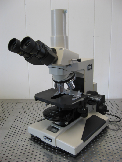 Photo d'un microscope optique tout ce qu'il y a de plus classique, comme ceux qu'on peut manipuler au lycée. On voit qu'il y a deux oculaires pour permettre d'y poser les deux yeux à la fois, et qu'on peut choisir entre plusieurs objectifs pour jouer sur le grossissement. L'image vient de la page Wikipédia sur les microscopes optiques.
