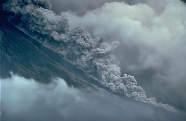 Photo d'une nuée ardente trouvée sur la page Wikipédia qui leur est dédiée, et qui provient de l'éruption du Mayon aux Philippines en 1984. On voit un flanc de montagne avec pas mal de fumée autour, mais un nuage de gaz en particulier dévale la pente du volcan un peu comme le ferait une coulée de lave.