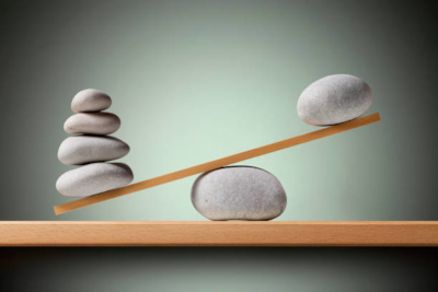 Photo d'une balance faite avec des pierres, et déséquilibrée : il y a beaucoup plus de pierres d'un côté que de l'autre, ce qui la fait pencher. Photo d'une balance faite avec des pierres, et déséquilibrée : il y a beaucoup plus de pierres d'un côté que de l'autre, ce qui la fait pencher.