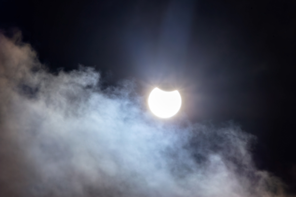 Photo, trouvée sur Wikimédia Commons, d'une éclipse partielle de Soleil prise en Suède le 29 mars 2025. On voit dans le ciel pas mal de nuages, la plupart en bas de l'image, mais surtout une grosse boule lumineuse dont il manque une partie en haut, la Lune commençant à cacher notre Soleil. Il ne manque qu'un tout petit bout de l'étoile, et donc, à moins de spécifiquement savoir qu'il se passe quelque chose et d'être en train de l'observer avec du matériel adapté, les chances de remarquer quoi que ce soit sont plutôt basses dans ce genre de cas.