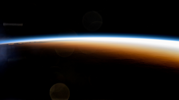 Photo de l'atmosphère de la Terre, prise depuis la station spatiale internationale et trouvée sur Wikimédia Commons. L'image est prise au niveau du terminateur, et la partie basse est noire car totalement dans l'ombre (la partie du haut est noire aussi, mais ça, c'est l'espace). Dans le lointain, on voit l'atmosphère au dessus de la partie éclairée de la Terre, qui est bleu-blanc et fait as mal de lumière, mais à la limite de l'ombre, on peu voir une partie du ciel colorée de rouge et de jaune, et nous envoie aussi pas mal de lumière, même si très nettement moins que l'autre. C'est celle lumière-là qui donne sa couleur à la Lune pendant les éclipses.