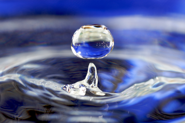 Photo d'une surface d'eau liquide un peu agitée avec une goutte bien visible au dessus d'elle, qui illustre actuellement la page Wikipédia sur l'état liquide.