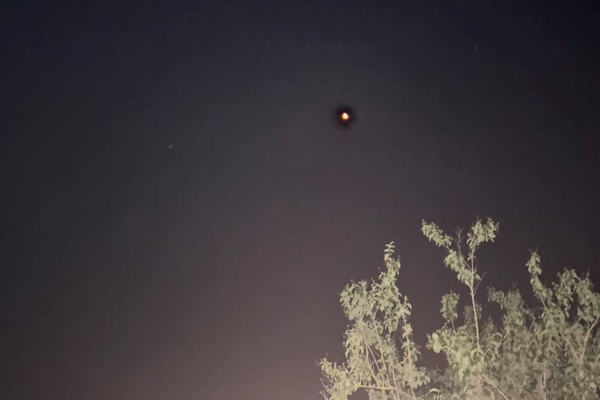 Photo prise à Achères, dans les Yvelines, le 22 juin 2025, et trouvée elle aussi sur le site du GEIPAN. On voit quelques plantes éclairées en bas, et en haut un ciel nocturne avec peu d'étoiles, mais ce qui ressemble à une flamme en train de brûler au milieu de rien. Il s'agit en l'occurrence d'une lanterne thaï isolée.