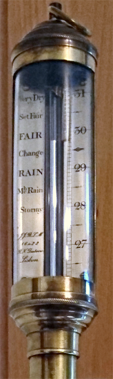 Zoom sur un baromètre à mercure, semblant être du modèle inventé par Torricelli. On voit un tube de métal contenant une certaine quantité de mercure, à côté duquel on voit des inscriptions comme « rain » (pluie) ou « fair » (beau temps). En effet, la météo est liée aux conditions atmosphériques, et notamment aux variations de la pression de l'air (on parle de « dépression » par opposition aux « anticyclones », par exemple) et mesurer les variations de cette pression, et donc de la hauteur du mercure dans le tube, permet d'anticiper un peu le temps qu'il va faire, comme Guericke l'avait compris.