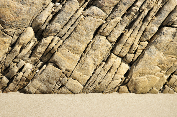 Photo de roches sédimentaires trouvées sur Wikipédia (il s'agit précisément de couches de grès près de Port Nolloth en Afrique du Sud). Là, visiblement, il y a eu un séisme ou quelque chose comme ça, puisque ces couches sont assez ostensiblement de biais, et pas du tout parallèles au sol. Néanmoins, on voit toujours l'organisation en couches successives et on continue de voir l'ordre chronologique en suivant les différentes couches.