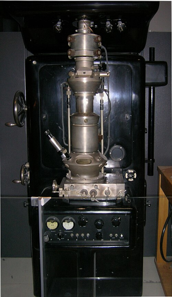 Photo d'un microscope électronique de 1933, trouvé sur la page Wikipédia dédiée à ce type d'instruments. On voit qu'on retrouve globalement les mêmes éléments extérieurs, un oculaire pour la vue et des machins à tourner pour régler les détails, mais il s'agit d'un objet beaucoup plus grand et encombrant, et cette fois-ci la zone où poser l'échantillon n'est pas à l'air libre.