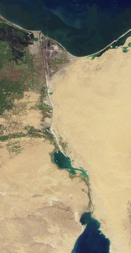Vue par satellite du Canal de Suez, trouvée sur la page Wikipédia qui lui est dédiée. On voit un bout de la mer Rouge en bas, de la Méditerranée en haut, et entre les deux, une surface majoritairement désertique (la seule exception étant la zone au nord-ouest), mais traversée par un canal navigable plus ou moins rectiligne, avec quand même un gros lac naturel au milieu. Ce canal semble plutôt étroit vu depuis l'orbite terrestre, et arriver à en détecter des traces au télescope depuis Mars ne semble pas particulièrement vraisemblable, ce qui nous donne peut-être un indice pour la suite.