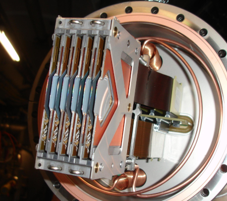 Photo d'un des détecteurs du LHC, trouvée sur Wikimédia Commons. Je vais avoir un peu de mal à décrire, on voit un truc circulaire avec du câble dedans, qui s'enroule en bobine en haut et en bas, avec une sorte de boitier métallique à plusieurs compartiments qui dépasse. En tout cas, ça ne ressemble pas du tout à un simple oculaire pour poser son œil.